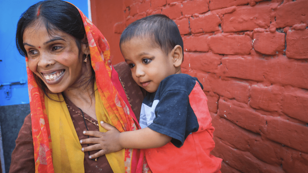 An Indian woman living in the slums of Delhi poses with her child | Photo by Simit Bhagat